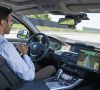 Ein Mitarbeiter von BMW sitzt am Steuer eines autonomen BMW-Fahrzeugs.