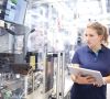 Mitarbeiterin mit Tablet steht an einer Industrieanlage in einem Werk von Bosch