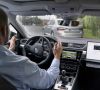 Ein Mann sitzt am Steuer eines autonomen Skoda-Fahrzeugs und folgt einem vorausfahrenden Pkw.
