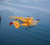 Eine Drohne von DHL liefert ein Paket aus und fliegt dabei über Wasser.