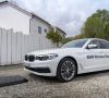 Ein weißer BMW steht vor einer Matte zum induktiven Laden für Wireless Charging.