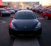Tesla Model 3 auf einem Parkplatz mit Ladesäulen von Tesla.