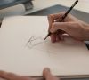 Eine Hand fertigt eine Design-Skizze eines Audi-Fahrzeugs auf einem Blatt Papier an