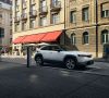 Ein Mazda MX-30 steht an einer Ladesäule an der Straße vor einer Häuserfront.